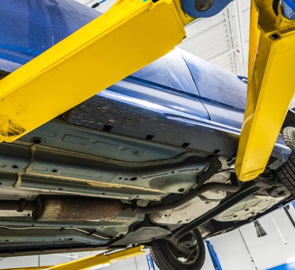 Closeup of a Blue Car Being Lifted at the Auto Service Center. Checking the Underside of the Vehicle Before Starting the Repair Work. Car Maintenance Theme.