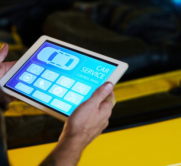 Hands of male mechanic of maintenance service holding tablet with homepage with icons on screen while standing by car